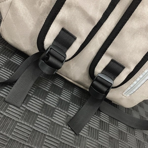 Close-up of adjustable straps and high-strength plastic buckles on a beige canvas backpack