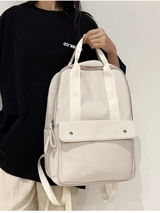 Close-up of lightweight beige backpack with top handles and stylish metal buckle detail