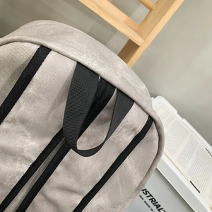 Detail of reinforced black handle and shoulder strap on a grey canvas backpack