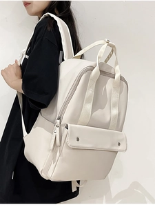 Detailed view of cream nylon backpack on model showing side profile and large capacity