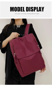 Close-up of a burgundy nylon backpack with large flap and dual side zipper closure
