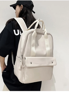 Side view of cream leather laptop backpack on model featuring a large front flap pocket