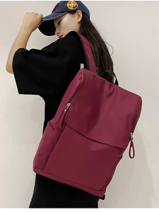 Detail view of a burgundy travel backpack with waterproof fabric on a female model
