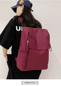 Detailed side view of a large burgundy backpack with flap closure and zip pulls