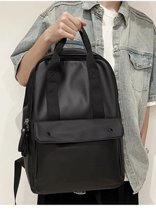 Close-up of matte black leather backpack with dual buckle flap and top handle on model