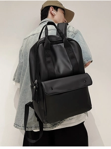 Close-up of black matte PU leather backpack featuring large snap-button front pocket detail
