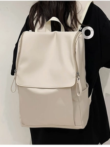 Minimalist beige waterproof nylon backpack with large flap and dual side zippers shown on model