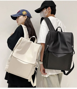 Detail of minimalist nylon flap backpack with side pockets in black and off-white colors