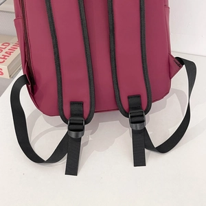 Detail of padded burgundy shoulder straps with black adjustable buckles on large backpack