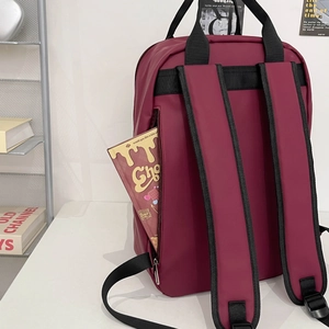 Detail of burgundy waterproof backpack with adjustable straps on a modern minimalist desk
