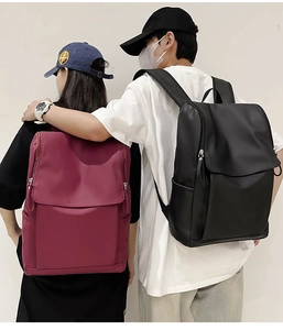 Rear view of black and burgundy waterproof backpacks worn by models in a minimal setting
