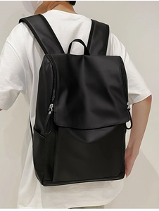 Minimalist black backpack showing adjustable shoulder straps and top handle from a back view