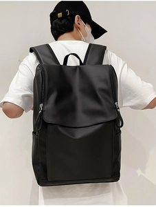 Rear view of model wearing a black matte leather backpack with wide straps and top handle