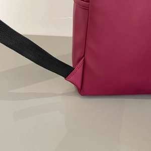 Detail view of reinforced stitching and black nylon strap on magenta travel backpack