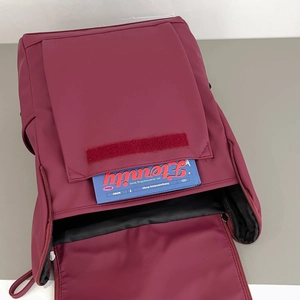 Detail view of burgundy backpack front pocket with velcro closure and open main compartment