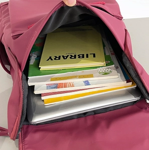 Interior detail of a burgundy travel backpack showing a laptop compartment and books