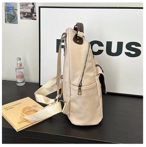 Side view of beige leather backpack with brown trim and vintage gold zippers