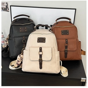 Three vintage faux leather backpacks in black, cream, and brown with cat charms