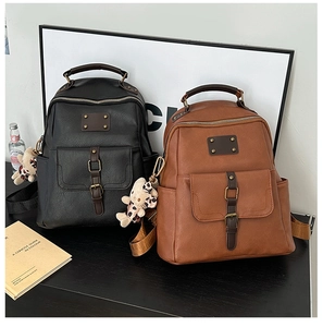 Detail of vintage PU leather backpack with buckle pockets, rivets and cute bear pendant