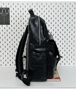 Detailed side view of black leather backpack showing metallic zippers and thick straps