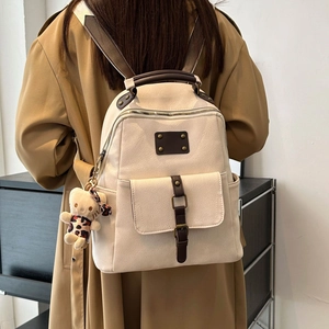 Minimalist beige faux leather backpack with vintage brown straps and a cute bear charm