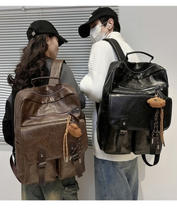 Detail of vintage faux leather backpacks in black and brown with plush bear charms