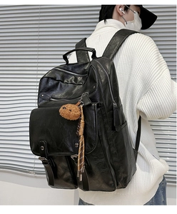Close-up of black PU leather backpack showing texture and plush bear charm detail