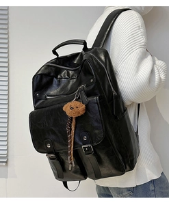 Detail view of large black faux leather backpack with teddy bear charm for students