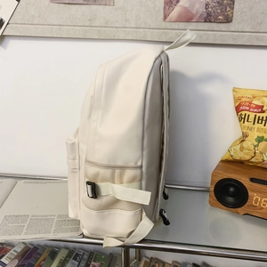 Detail of cream soft leather backpack showing side buckle pocket and mesh bottle holder