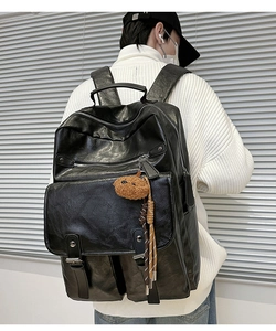 Detail of black PU leather backpack with multiple zipper pockets and brown bear charm