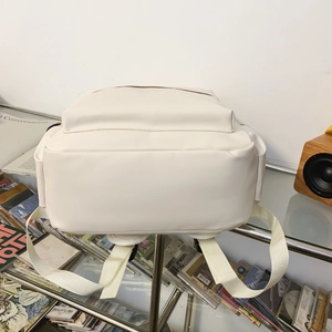 Detail view of cream PU leather backpack with sturdy fabric straps and spacious base