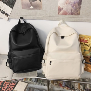 Detail of minimalist matte PU leather backpacks in black and beige on a glass shelf