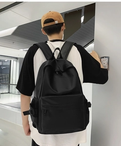 Close-up of black minimalist backpack featuring large front pocket and side buckle straps