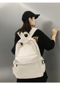 Detail of minimalist beige faux leather backpack showing front zipper pocket and mesh side pockets