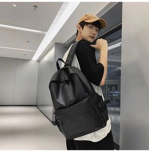 Side view of a minimalist black faux leather backpack shown on a model in a modern hallway