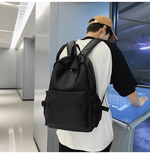 Detail of minimalist black soft leather backpack showing side buckle and large front pocket