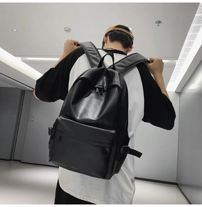 Male model wearing black faux leather backpack in a modern urban corridor setting