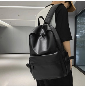 Rear side view of a minimalist black faux leather backpack worn for school or commute