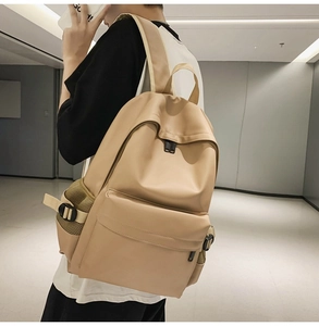 Side view of a beige soft leather minimalist backpack featuring large front pocket and mesh side