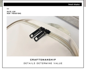 Detailed close-up of smooth cream synthetic leather and black metal double zipper closure