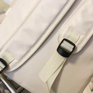 Detail of soft off-white backpack strap with breathable mesh and adjustable buckle