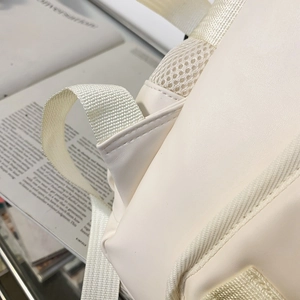 Detail of soft PU leather backpack featuring breathable honeycomb mesh back and woven handle