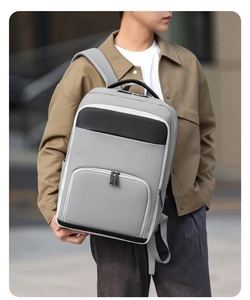 Man wearing grey water-resistant commuter backpack with adjustable straps in city street