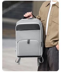 Close-up of a gray waterproof business backpack held by a model in a modern urban city setting