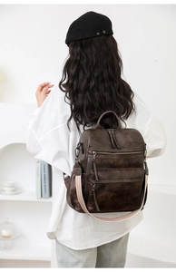 Primer plano de mochila retro de cuero marrón oscuro con cremalleras y correas decorativas