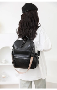 Detalle de mochila de cuero sintético negro con correa de jacquard y bolsillos con cremallera