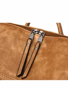 Detalle de cremallera doble con tiradores de cuero en mochila de color marrón