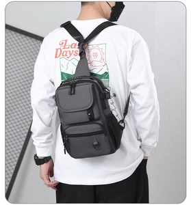 Detail view of water-resistant nylon chest bag with multiple pockets on a male model