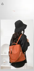 Detail of orange woven anti-theft backpack showing PU texture and wide shoulder strap