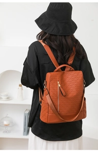 Brown faux leather anti-theft backpack with 3D geometric texture shown on a model